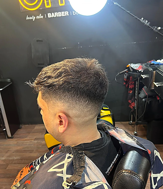 Corte con degradado en los lados y volumen arriba, visto de lado con el letrero one al fondo